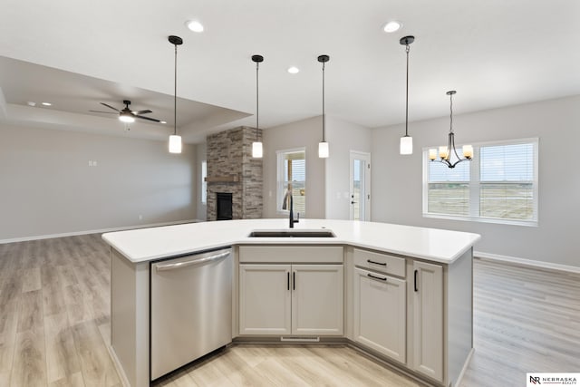 kitchen featuring a sink, open floor plan, dishwasher, a fireplace, and ceiling fan with notable chandelier