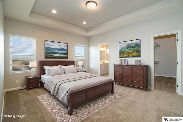 bedroom featuring a raised ceiling, baseboards, recessed lighting, light carpet, and a spacious closet