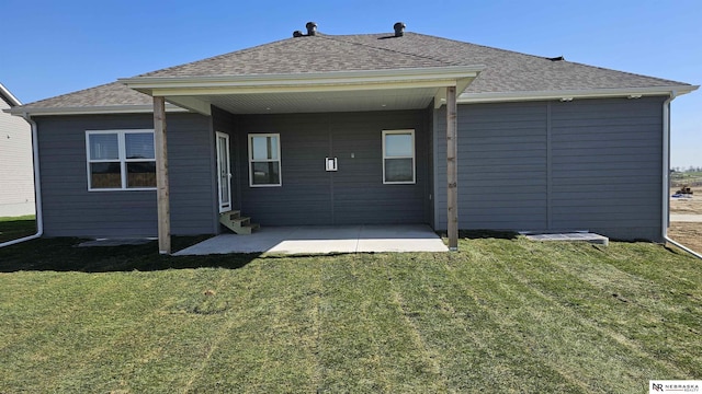 rear view of property with a yard, entry steps, and roof with shingles