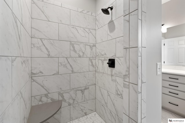 full bath featuring tiled shower, marble finish floor, and vanity