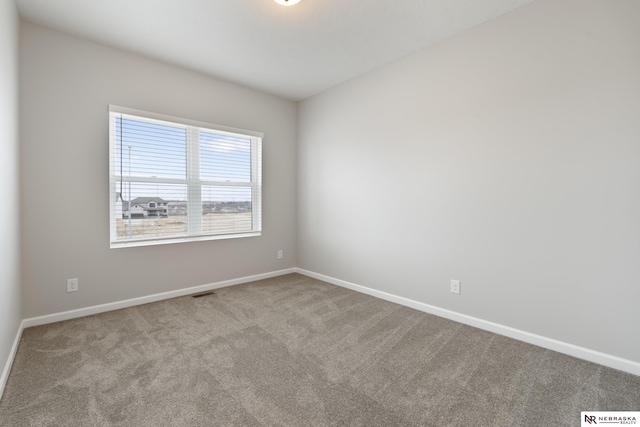 carpeted spare room featuring baseboards and visible vents