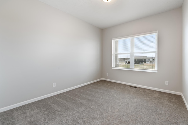 carpeted spare room with visible vents and baseboards
