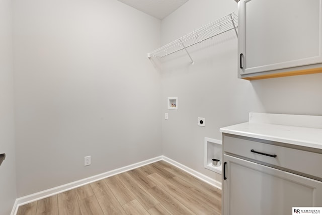 clothes washing area featuring electric dryer hookup, cabinet space, washer hookup, light wood finished floors, and baseboards