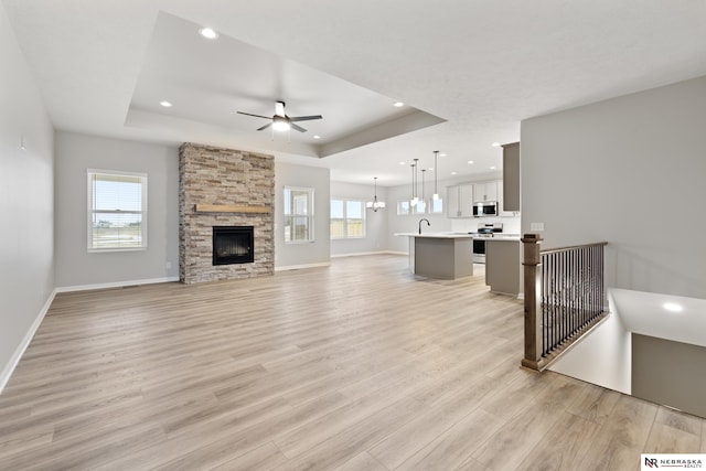 unfurnished living room featuring recessed lighting, a raised ceiling, and a ceiling fan