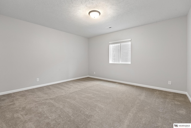spare room with a textured ceiling, baseboards, and carpet floors