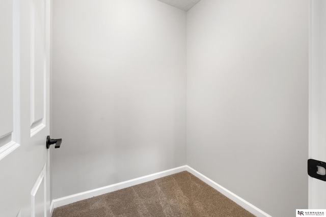 spare room with baseboards and dark carpet