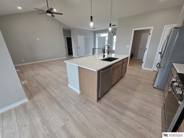 kitchen with stainless steel appliances, light countertops, a sink, a ceiling fan, and open floor plan