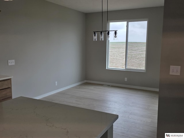 unfurnished dining area featuring baseboards, visible vents, and light wood-style floors