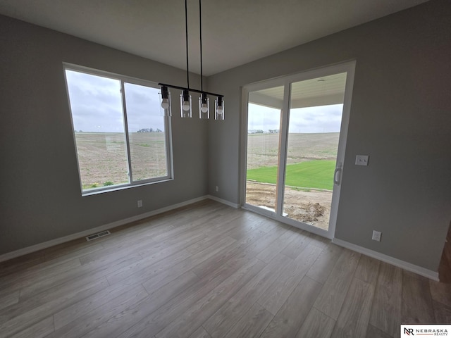 unfurnished dining area featuring wood finished floors, visible vents, and baseboards