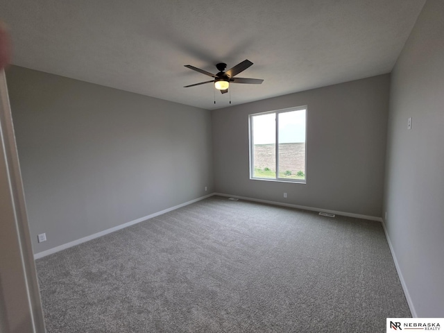 carpeted spare room with ceiling fan and baseboards