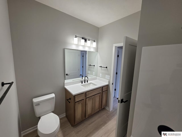 bathroom featuring wood finished floors, toilet, vanity, and baseboards
