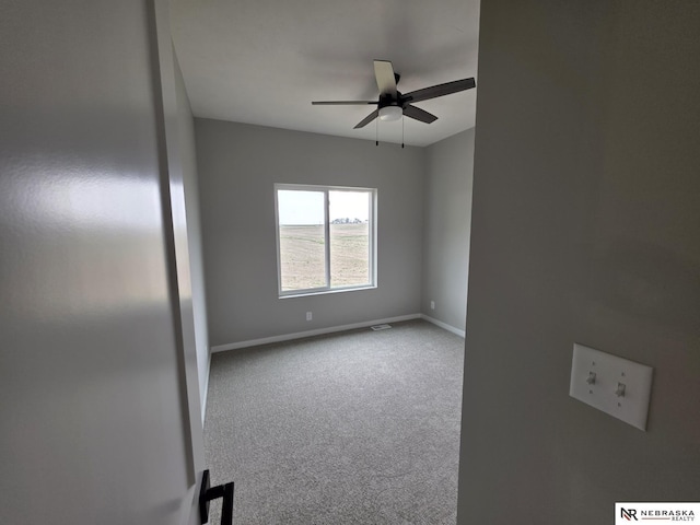 unfurnished room with carpet, visible vents, a ceiling fan, and baseboards