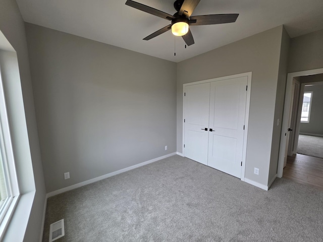 unfurnished bedroom featuring carpet flooring, a closet, a ceiling fan, visible vents, and baseboards