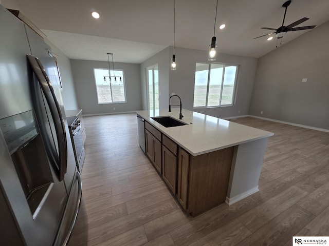 kitchen featuring a sink, light wood-style floors, baseboards, appliances with stainless steel finishes, and open floor plan