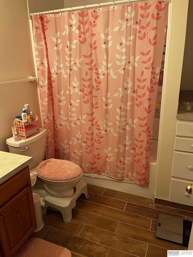 full bath featuring shower / tub combo, vanity, toilet, and wood finish floors