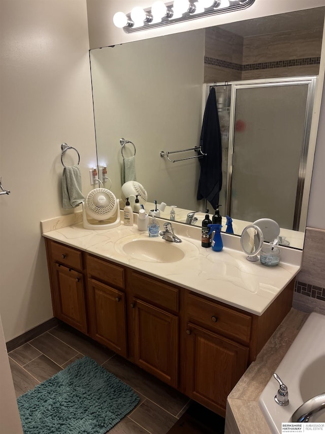 full bath with a tub to relax in, wood finish floors, a shower stall, and vanity