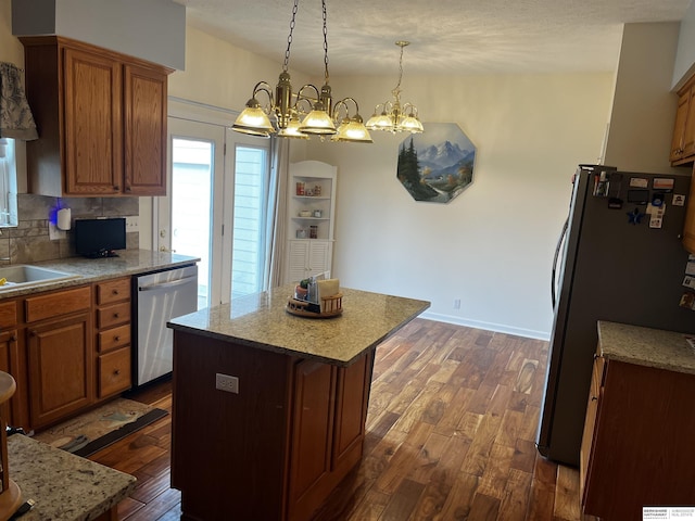 kitchen featuring brown cabinetry, stainless steel appliances, dark wood-style floors, and a sink