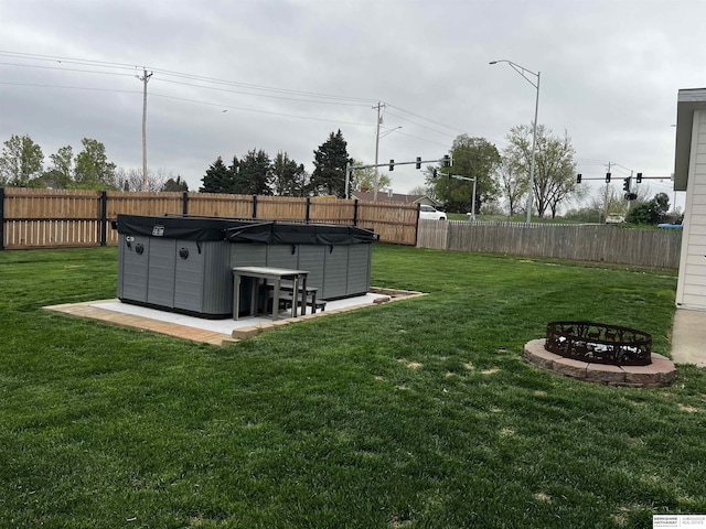 view of yard featuring a fire pit, a fenced backyard, and a hot tub