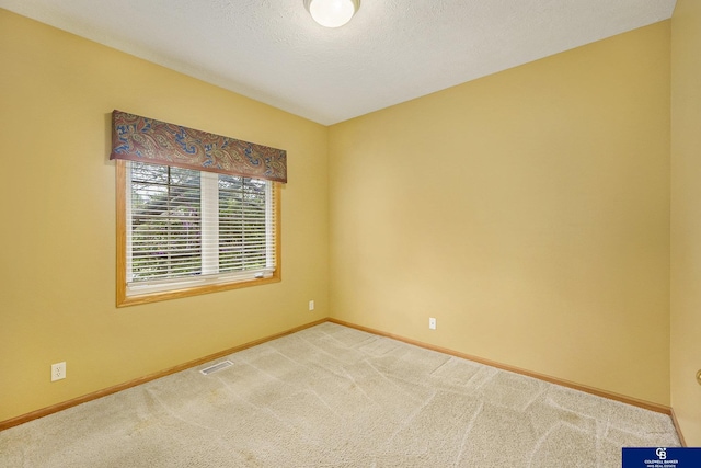 carpeted empty room featuring a textured ceiling, baseboards, and visible vents