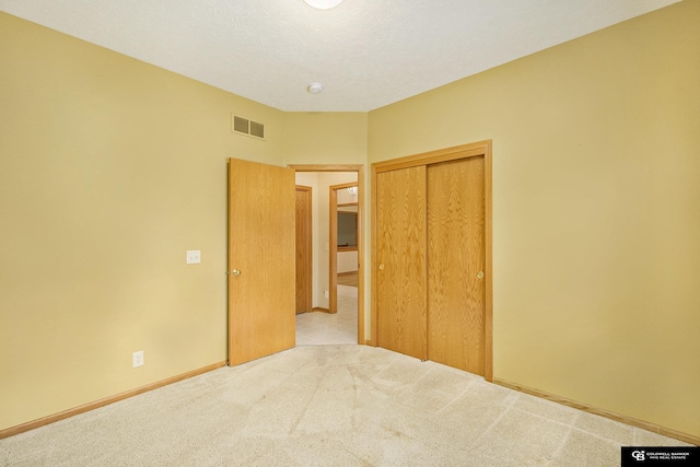 unfurnished bedroom featuring baseboards, carpet, a closet, and visible vents