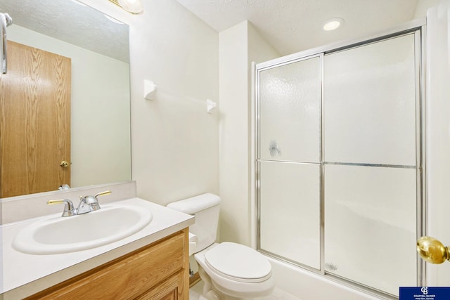 full bath featuring vanity, a shower stall, toilet, and a textured ceiling