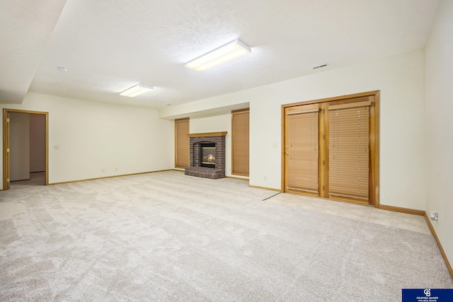 unfurnished living room with baseboards, light colored carpet, visible vents, and a fireplace