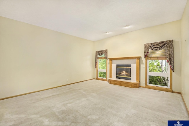 unfurnished living room featuring a tiled fireplace, baseboards, carpet flooring, and visible vents