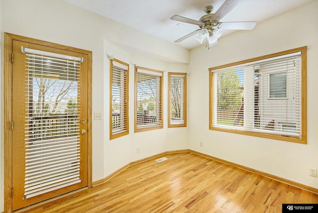 spare room featuring light wood-style floors, a ceiling fan, baseboards, and visible vents