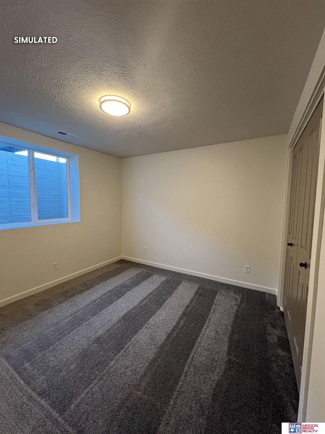 unfurnished bedroom featuring baseboards, visible vents, dark carpet, and a textured ceiling