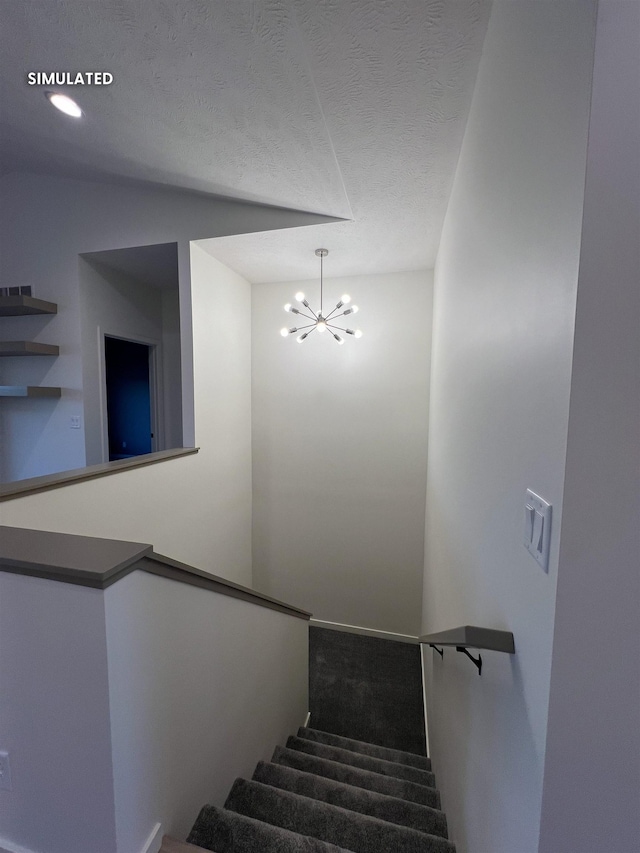 stairway with a textured ceiling and a chandelier
