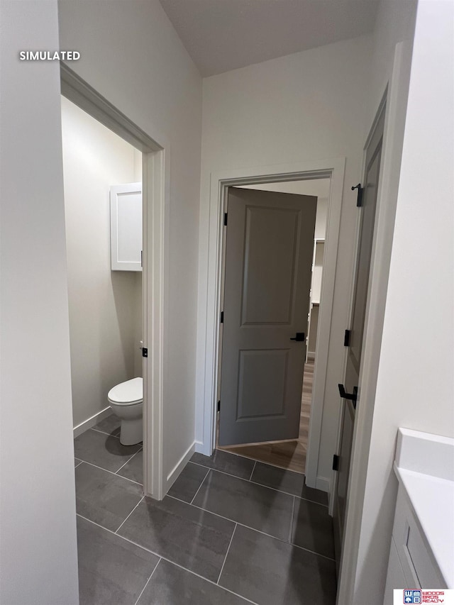 bathroom featuring toilet, tile patterned floors, and baseboards