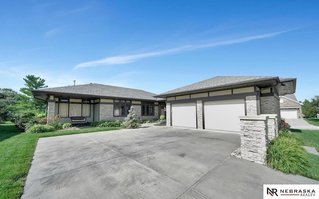 prairie-style house featuring concrete driveway, stone siding, and a front yard