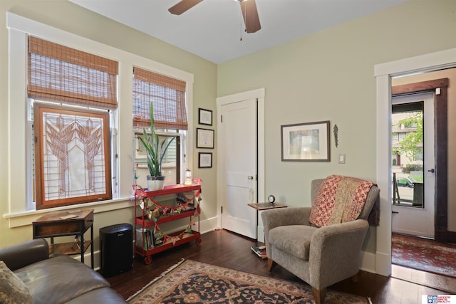 living area featuring baseboards, ceiling fan, and wood finished floors