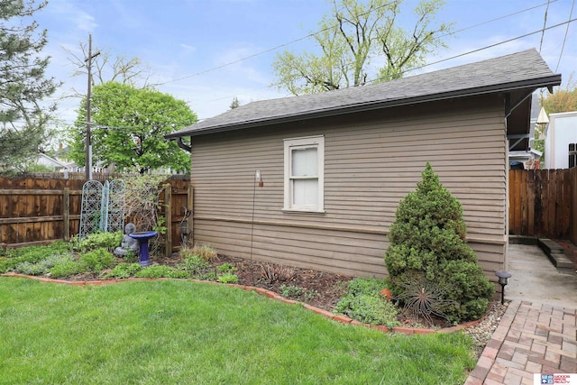 view of property exterior with fence, a shingled roof, and a yard