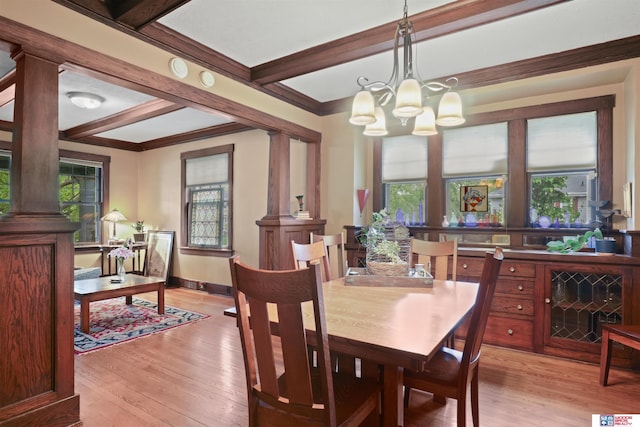 dining room featuring baseboards, decorative columns, light wood-style flooring, and a notable chandelier