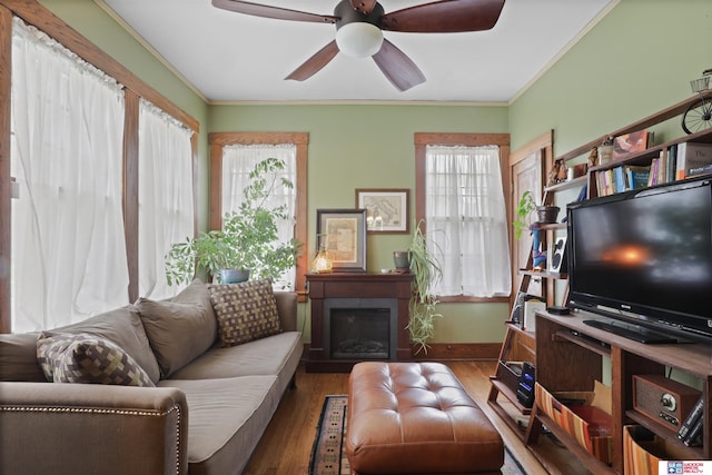 living room featuring crown molding, baseboards, a ceiling fan, and wood finished floors