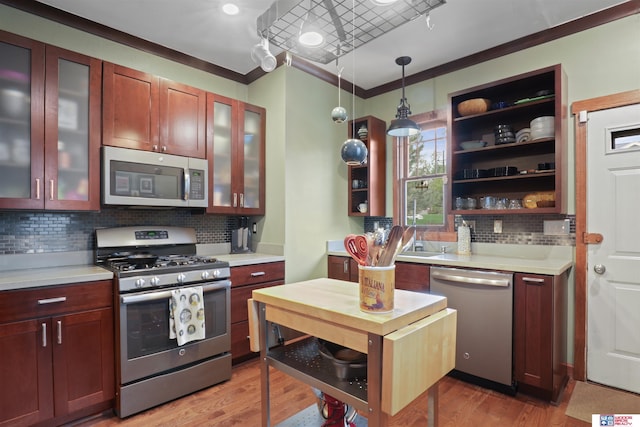 kitchen featuring light countertops, stainless steel appliances, crown molding, and light wood finished floors