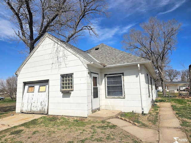 back of house featuring a shingled roof