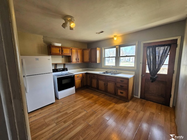 kitchen with a sink, range with electric cooktop, visible vents, light wood-style flooring, and freestanding refrigerator