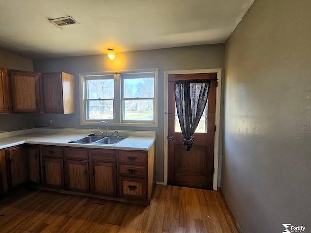 kitchen with dark wood finished floors, light countertops, brown cabinets, a sink, and visible vents