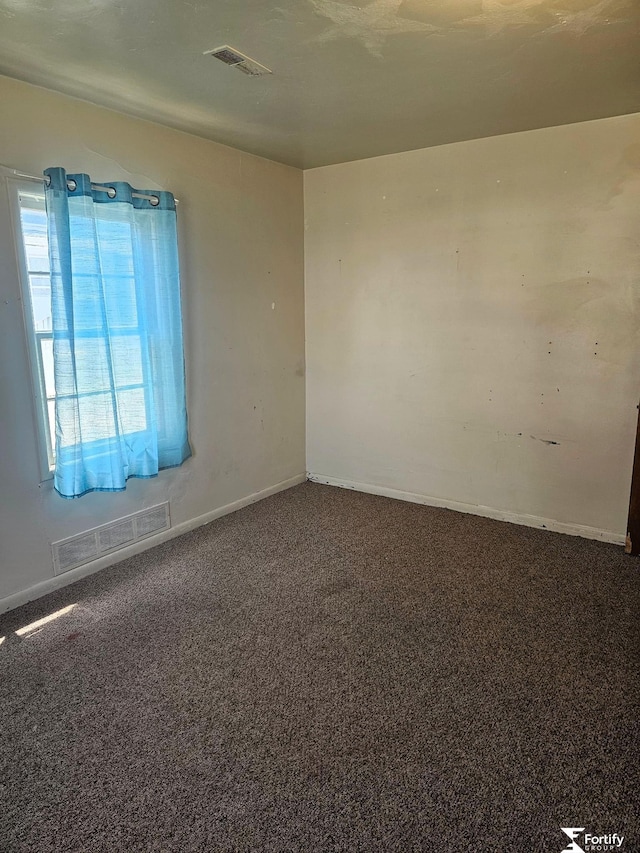 empty room with baseboards, visible vents, and carpet