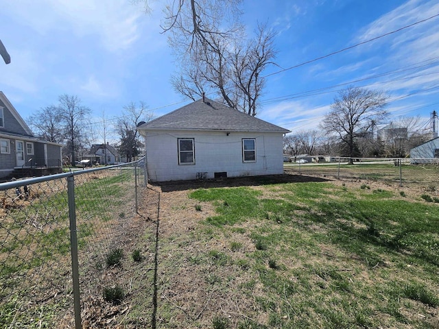 view of side of property with a yard, a shingled roof, concrete block siding, and a fenced backyard