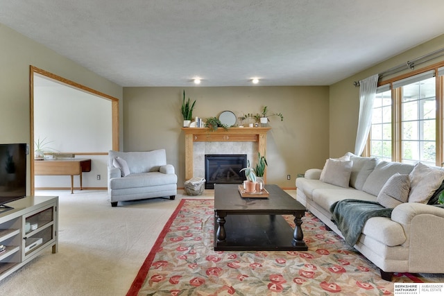 living room featuring a textured ceiling, baseboards, carpet, and a tile fireplace