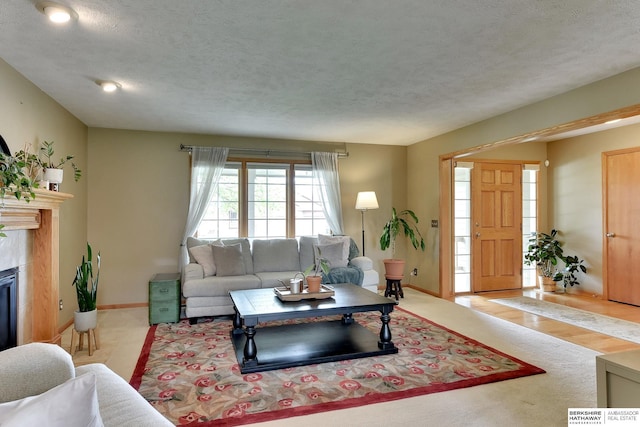 living room featuring baseboards, a textured ceiling, and a glass covered fireplace
