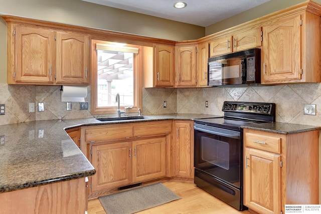kitchen with decorative backsplash, a sink, black appliances, and light wood-style floors