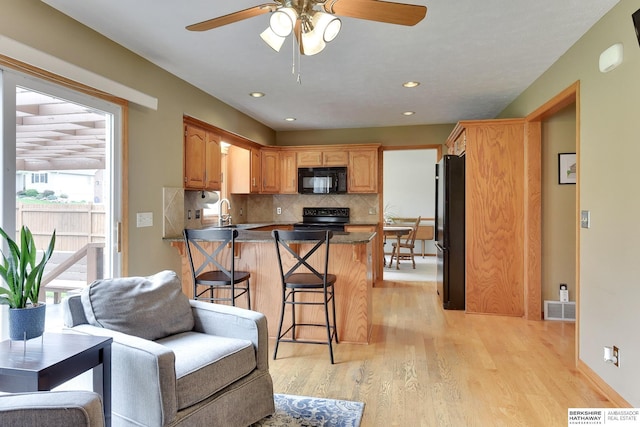 kitchen with a ceiling fan, visible vents, tasteful backsplash, black appliances, and a peninsula