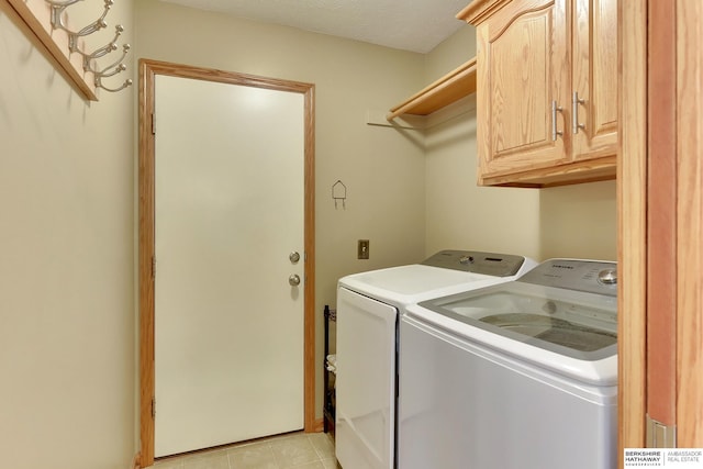 laundry area with cabinet space, light tile patterned floors, and washing machine and clothes dryer
