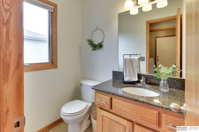 half bath with vanity, baseboards, tile patterned floors, and toilet