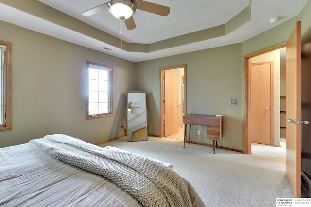 bedroom featuring carpet floors, visible vents, baseboards, ceiling fan, and a raised ceiling