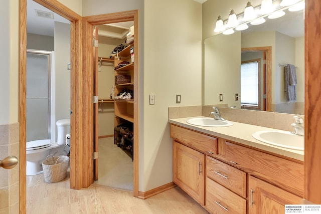 full bath featuring a walk in closet, visible vents, a sink, and a stall shower